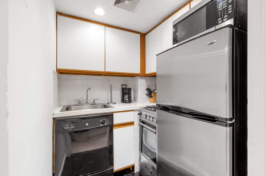 Small kitchen with refrigerator, stove, microwave, and sink.