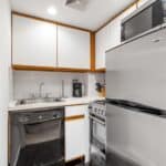 Small kitchen with refrigerator, stove, microwave, and sink.