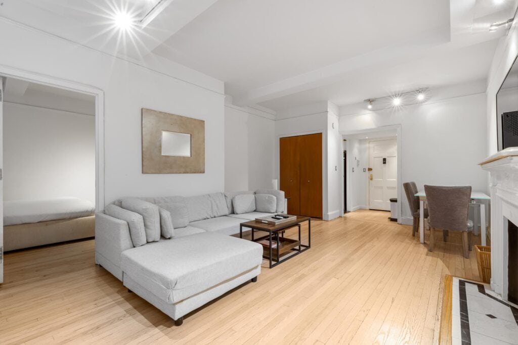 Bright living room with white walls, gray sofa, and wooden flooring.