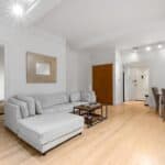 Bright living room with white walls, gray sofa, and wooden flooring.