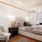Elegant bedroom with a large bed, nightstand, and cozy armchair.