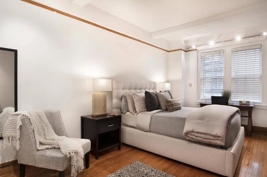 Elegant bedroom with a large bed, nightstand, and cozy armchair.