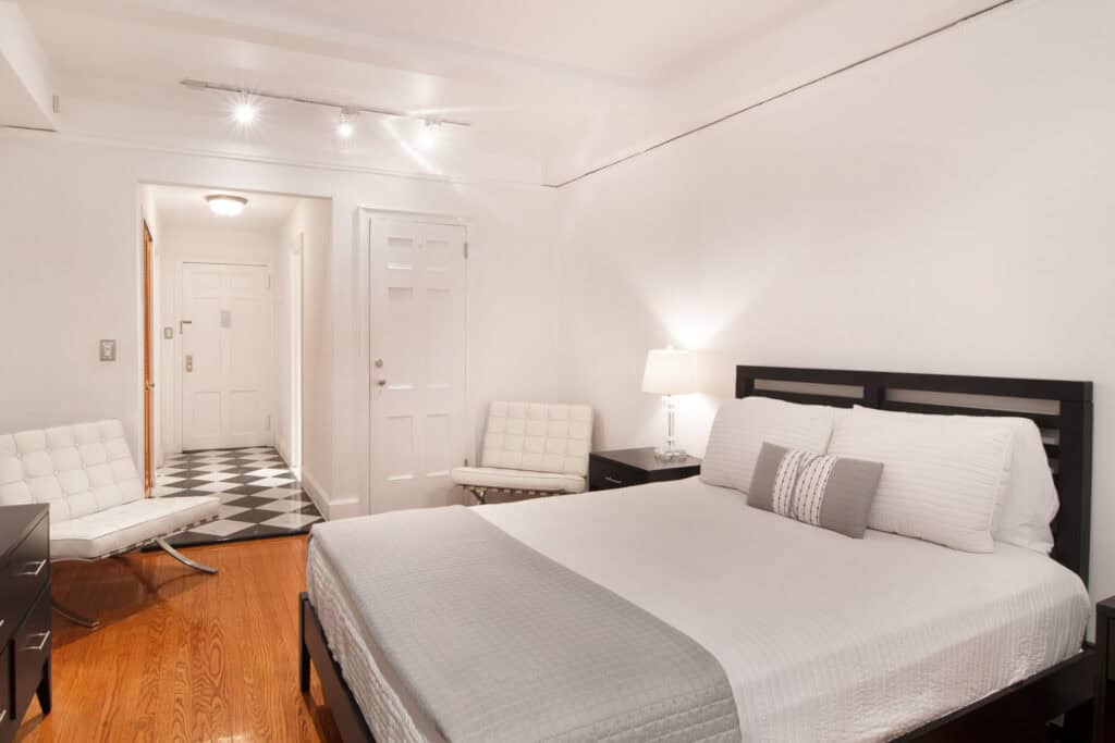 Spacious bedroom with white walls, black bed frame, and minimalist furniture.