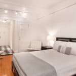Spacious bedroom with white walls, black bed frame, and minimalist furniture.