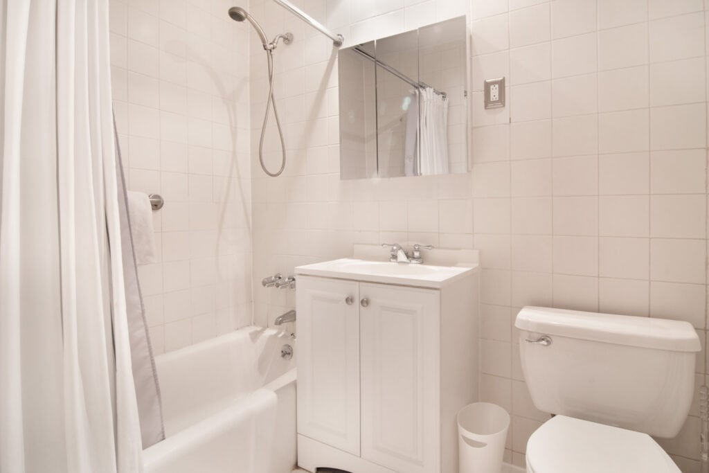 Compact bathroom with bathtub, toilet, and sink in a modern setting.