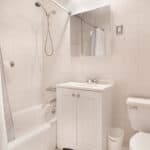 Compact bathroom with bathtub, toilet, and sink in a modern setting.