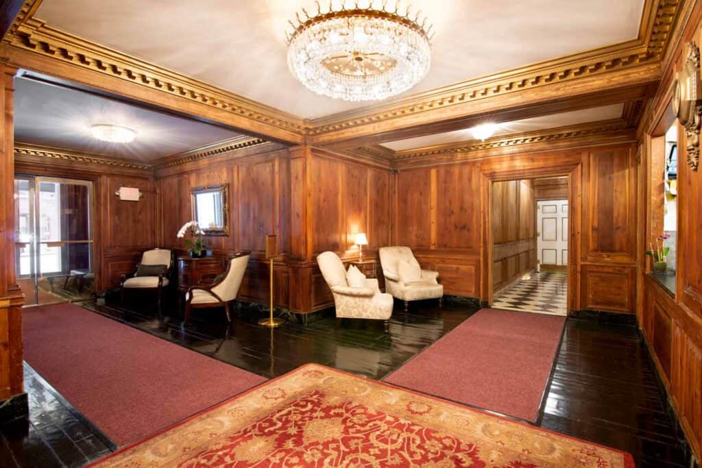 Luxurious lounge with wood paneling, chandelier, and classic furniture.