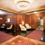 Luxurious lounge with wood paneling, chandelier, and classic furniture.