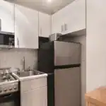 Compact kitchen with stove, refrigerator, microwave, and coffee maker.